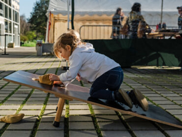 Une petite fille grimpe sur un grand jeu en bois en extérieur