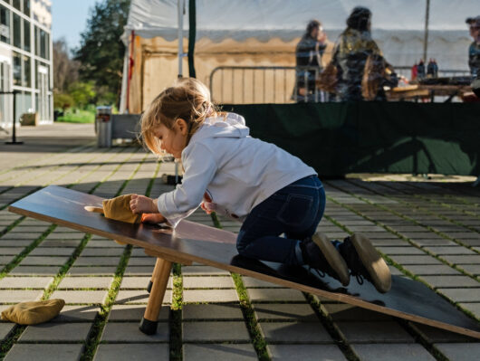 Une petite fille grimpe sur un grand jeu en bois en extérieur